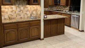 A kitchen with wooden cabinets, a tiled backsplash, and a stainless steel dishwasher. - Rare to find house of 5 BR and 4 Bath with big backyard in Fountain Valley.  (Fountain Valley)