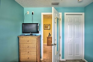 Cozy retreat with a television mounted on a dresser, a comfortable carpeted floor, and a small table with a decorative statue.