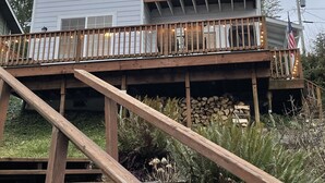 Une maison à deux étages avec une terrasse en bois et un escalier menant à celle-ci.