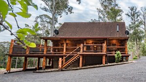 A wooden cabin with a porch, a staircase, and a satellite dish.