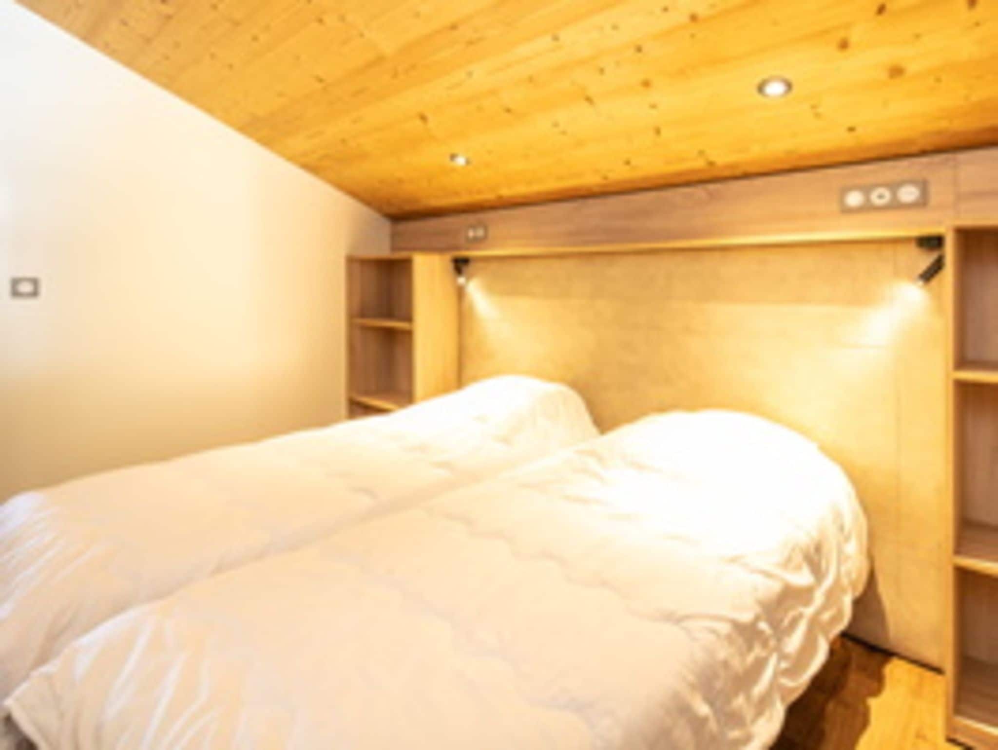 A bedroom with a bed, wooden headboard, and built-in shelving.