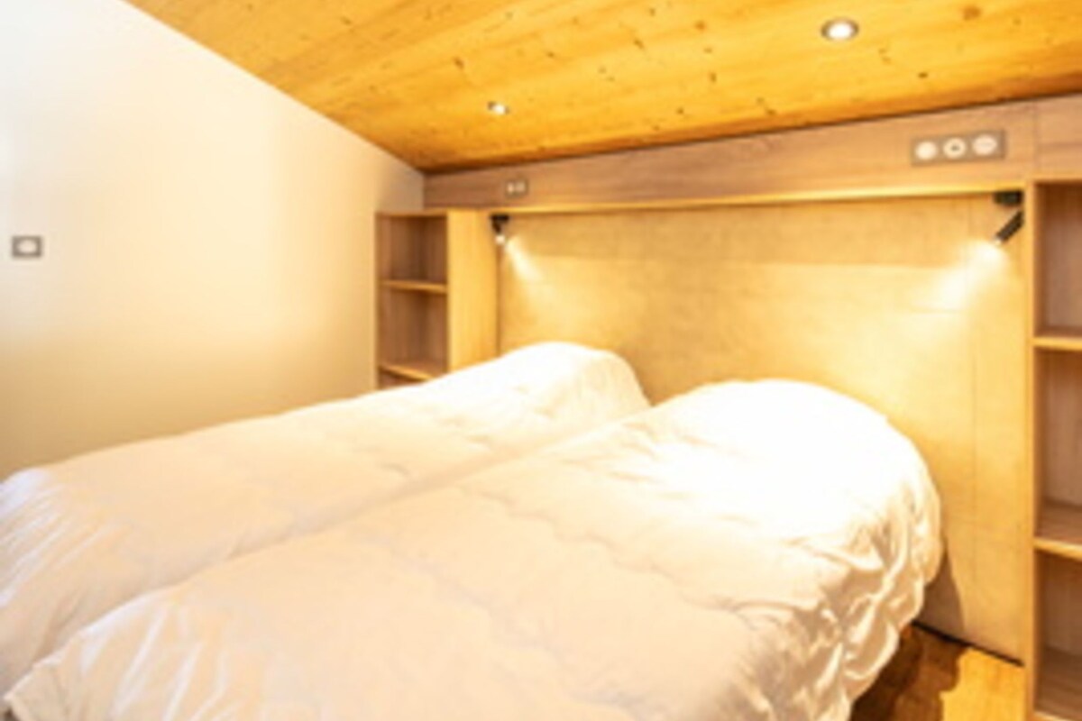 A bedroom with a bed, wooden headboard, and built-in shelving.