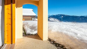 A snow-covered landscape with a mountain in the background and a building with a snow-covered roof.