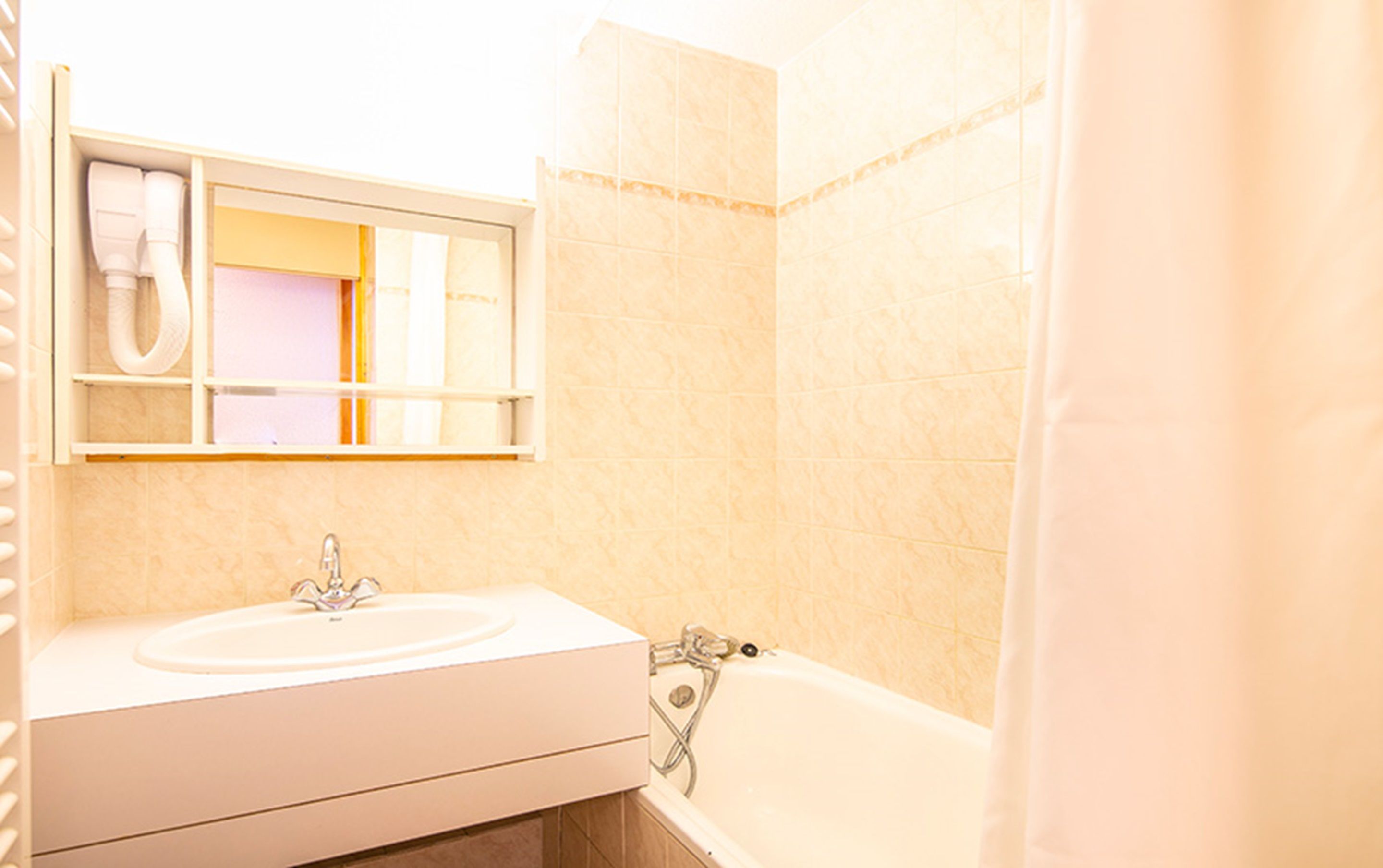 A bathroom with a sink, mirror, and bathtub.