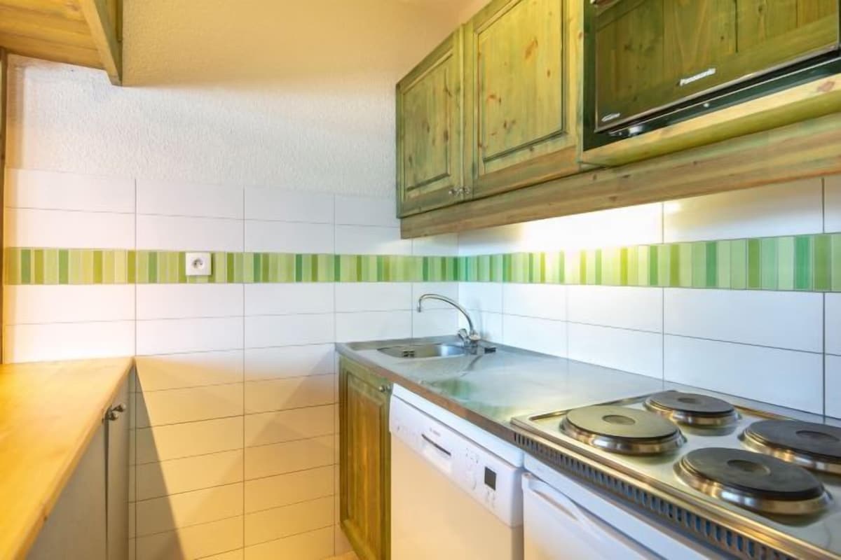 A kitchen with a stove, sink, and wooden cabinets.