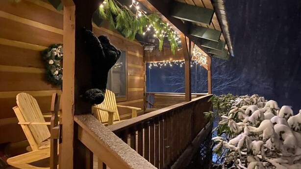 Uma cabana de madeira com varanda, luzes de fada e interior rústico.