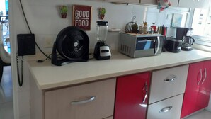 A kitchen with a microwave, blender, and fan on the counter. There are potted plants on the wall and a 'Good Food' sign. - Remodeled Gorgeous Apartment on Beach (Cartagena)