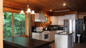 Una cocina moderna con armarios blancos, electrodomésticos de acero inoxidable y techo de madera.