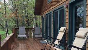 Una terraza de madera con mobiliario exterior y vistas a un área boscosa.