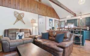 Ein rustikales Interieur mit Ledersofa, Holzbalkendecke und Küchenbereich.