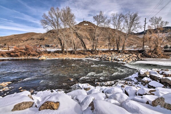 Un río con rocas cubiertas de nieve y una colina al fondo.