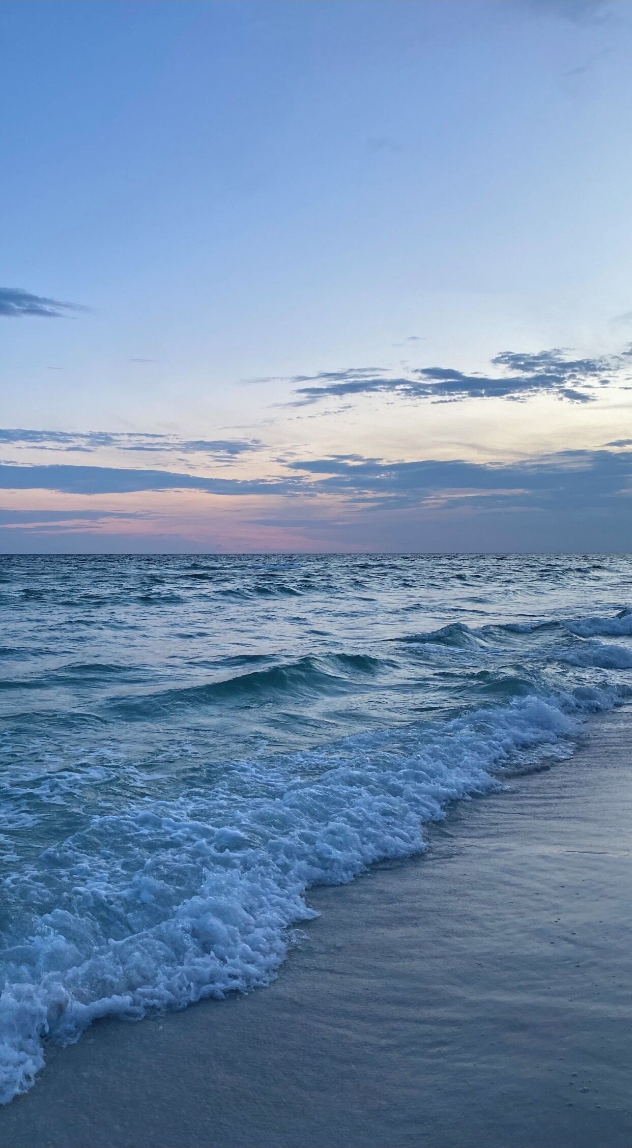 A beach with waves gently lapping onto the shore.