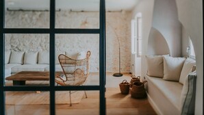 Ein modernes Wohnzimmer mit einem weißen Sofa, einem Holztisch und einem Korbstuhl.