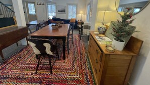 Un coin repas avec une table et des chaises en bois, un tapis coloré et un sapin de Noël.