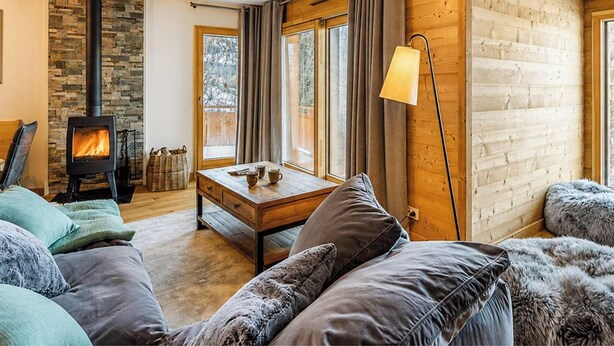 Ein gemütliches Wohnzimmer mit Kamin, Holzwänden, einer Couch und einem Tisch.