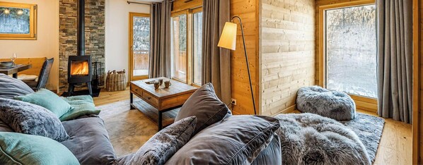 Ein gemütliches Wohnzimmer mit Kamin, Holzwänden, einer Couch und einem Tisch.