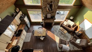 A spacious living area with a fireplace, a dining table, and a cozy seating arrangement. - Vista Getaway - Secluded country cabin, with wrap around porch and patio. (Klingerstown)