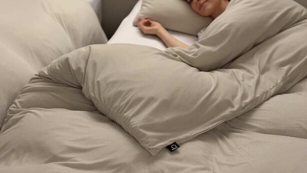 Una cama con una persona acostada, cubierta con una manta.