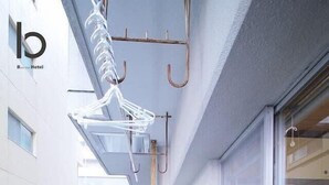 Un estrecho pasillo con barandilla metálica en un lado, puerta de cristal en el otro y un perchero colgado.