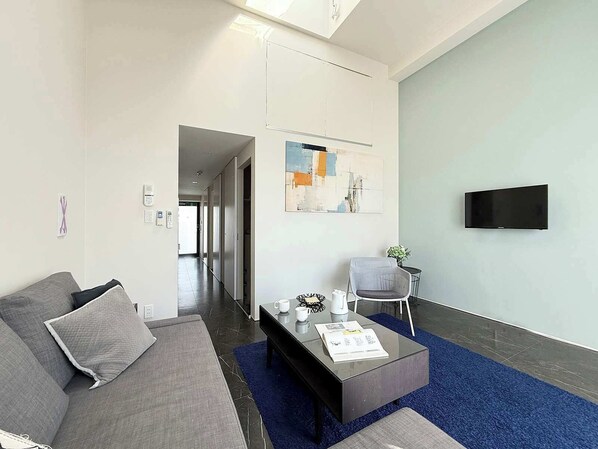 A modern living room with a sofa, coffee table, and a flat-screen TV.