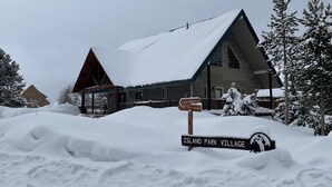 Un edificio cubierto de nieve con un cartel que indica 'N. DIG SPRINGS L. TWO TOP ROAD' y 'ISLAND PARK VILLAGE'.
