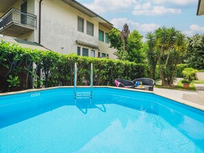 A swimming pool with a ladder, surrounded by greenery and a building with balconies. - Wonderful  villa for 8 people with WIFI, private pool, TV and pets allowed, close to Forte Dei M... (Pietrasanta)