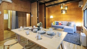 Un intérieur en bois comprenant une table à manger pour quatre personnes, un canapé et une petite table d’appoint.