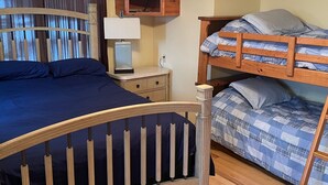 A bedroom with a curved wooden bed, a ceiling fan, a television, and a nightstand with a lamp. - Quiet Lake with Kayaks and Direct Beach Access! (Neshkoro)