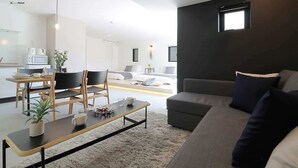 A modern hotel room with a dining area, a sofa, and a bed. - b hotel 1002 Exclusive Urban Penthouse Stay (Hiroshima City)