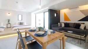 A modern living room with a sofa, a dining table with chairs, a bed, and a large window. - b hotel 902 Central Inner-Side Comfort Studio (Hiroshima City)