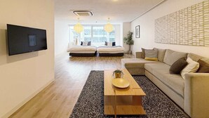 Una sala de estar moderna con un sofá, una mesa de centro y un televisor montado en la pared.