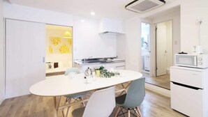 Una cocina moderna con electrodomésticos blancos, una mesa de comedor con sillas y una campana extractora visible.