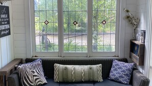 A cozy room with a dark blue sofa, three windows with diamond-shaped panes, and a sign on the wall.