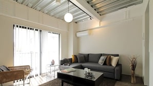 Ein modernes Wohnzimmer mit einem grauen Sofa, einem schwarzen Couchtisch und einem Korbstuhl.