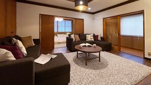 A modern living room with a sofa, a coffee table, and a large window. - b hotel Kaniwasou | Miyajima Island Stay 31 (Hiroshima City)
