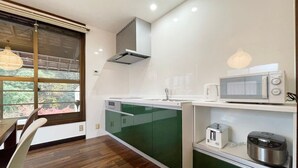 A modern kitchen with a green countertop, white cabinets, and a window with a view of greenery. - b hotel Kaniwasou | Miyajima Island Stay 31 (Hiroshima City)