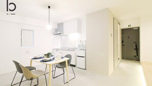 Une chambre d’hôtel moderne dotée d’un coin repas, d’une kitchenette et d’une porte donnant accès à la salle de bain.