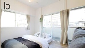 Una habitación de hotel moderna con una cama grande, un balcón con cortinas y vistas a la ciudad.