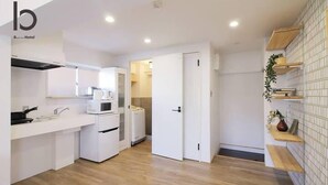 Una cocina moderna con armarios blancos, un microondas y una estufa. Hay una puerta que da a un baño.