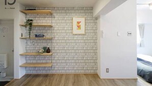 Una habitación de hotel con pared de azulejos, estantes de madera, un cuadro enmarcado y una cama.