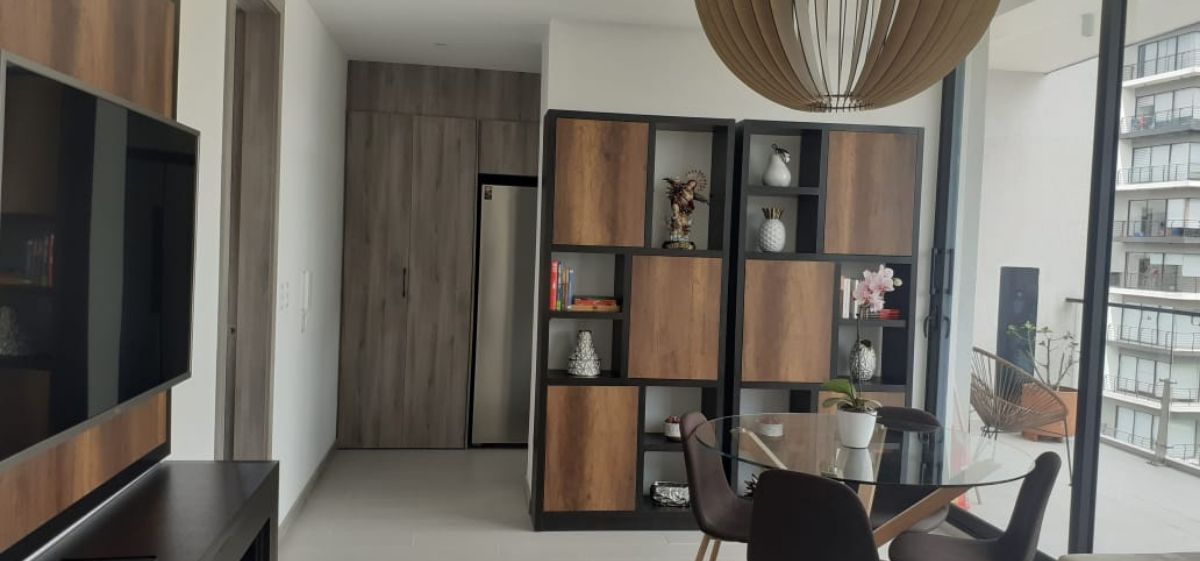Een moderne woonkamer met een flatscreen televisie, een glazen eettafel en een in de muur geïntegreerde houten boekenkast.