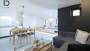 A modern hotel room with a dining area, a sofa, and a small kitchen.