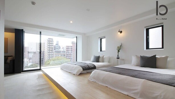 A modern hotel room with two beds, large windows, and a city view. - b hotel 601 Premium City View Apartment (Hiroshima City)