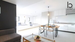 A modern hotel room with a living area, dining space, and kitchenette. - b hotel 601 Premium City View Apartment (Hiroshima City)