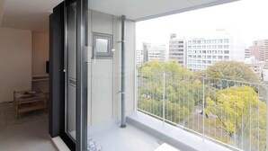 A balcony with a city view, a sliding door, and a small table with a plant. - b hotel 601 Premium City View Apartment (Hiroshima City)