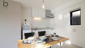 Een moderne keuken in een hotel met witte kasten, een magnetron, en een eethoek compleet met borden, glazen en bestek.