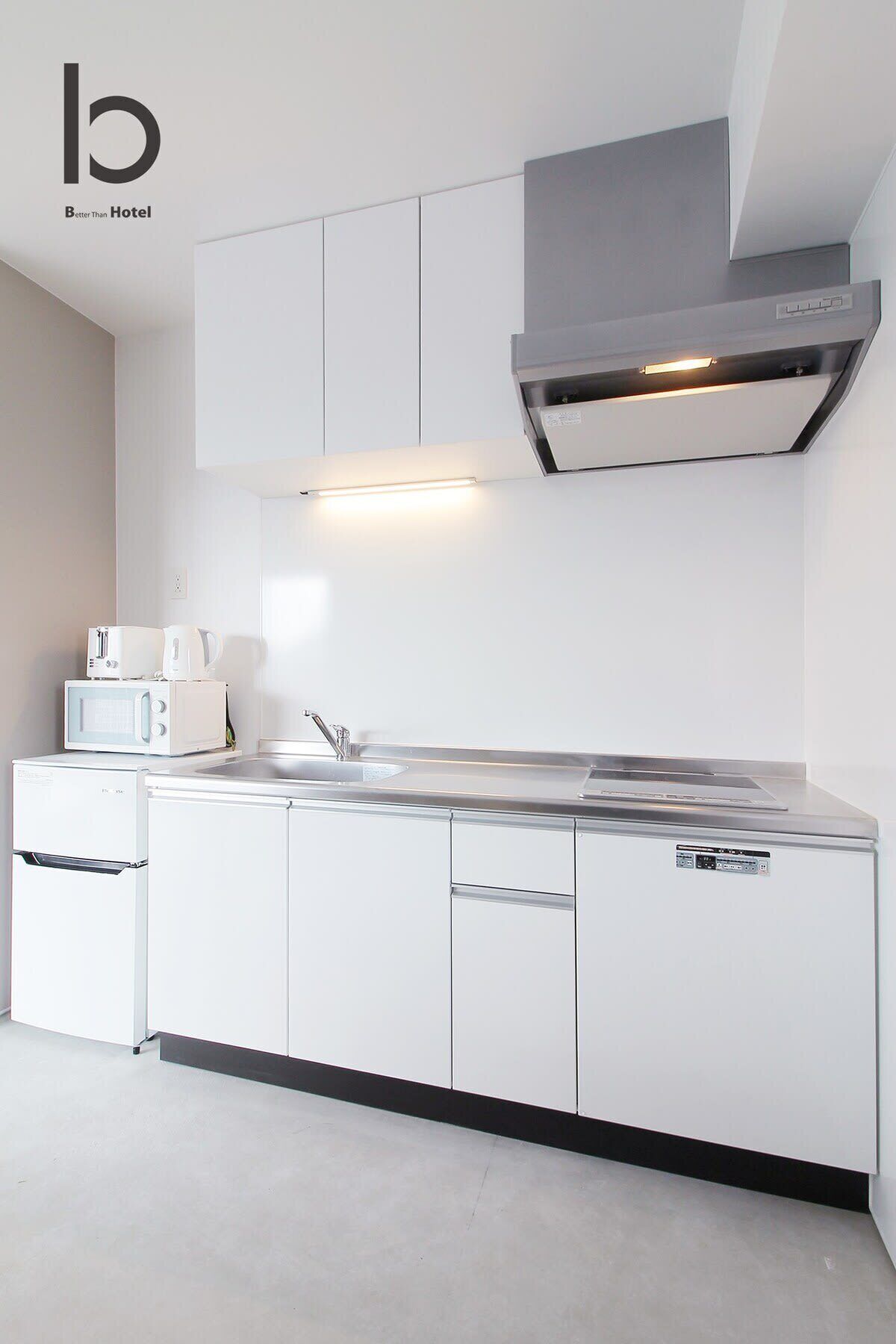 A modern kitchen with white cabinetry, a stainless steel range hood, a microwave, and a coffee maker on the counter.