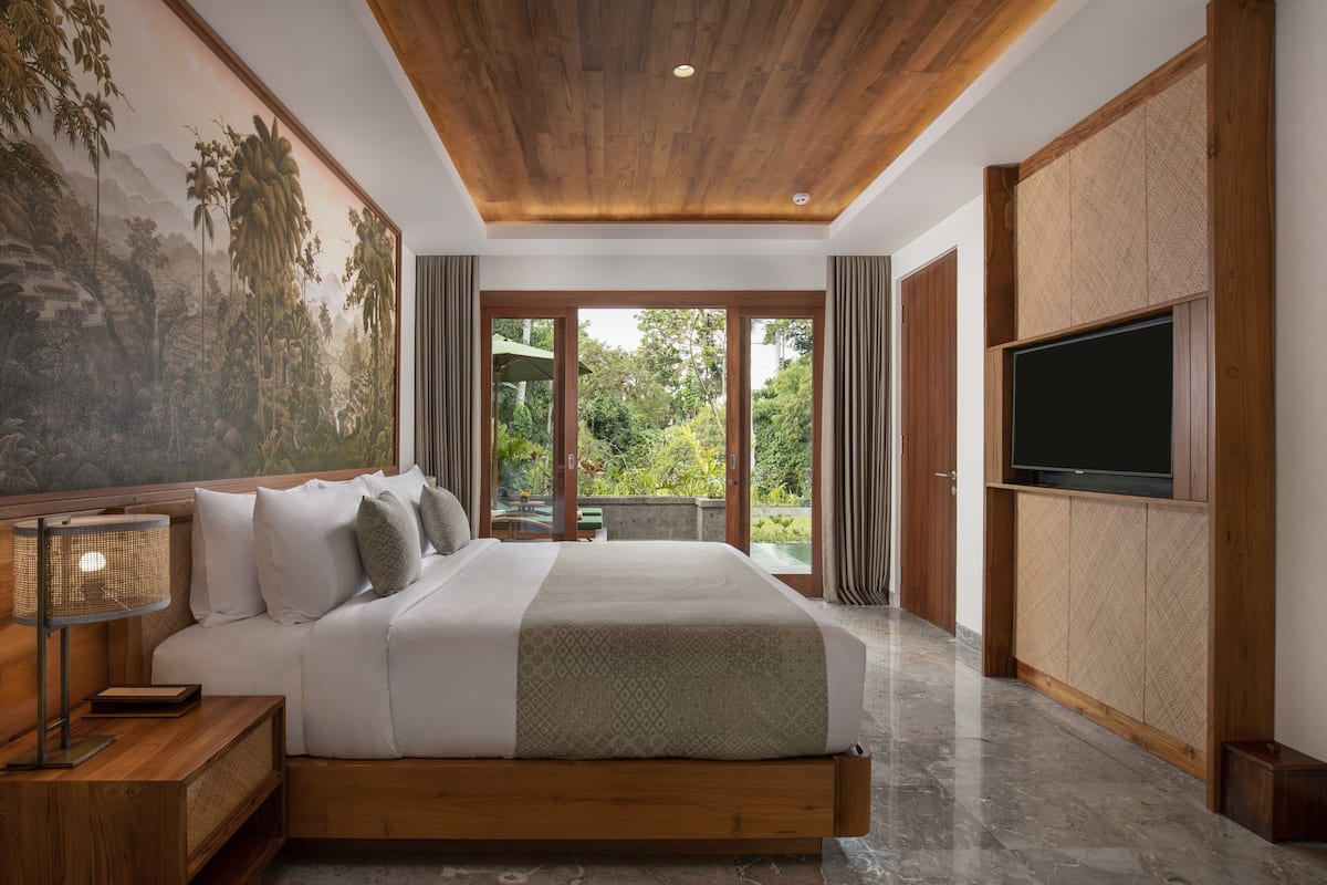 A bedroom with a large bed, a television, a nightstand, and a mural on the wall.