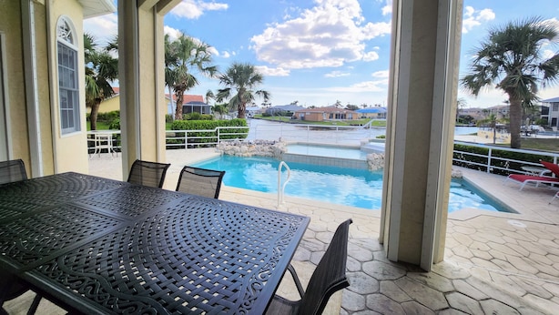 Pátio externo com piscina, mesa e cadeiras.