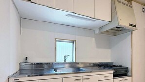 A compact kitchen with a built-in stove, a sink, and a window above the countertop.